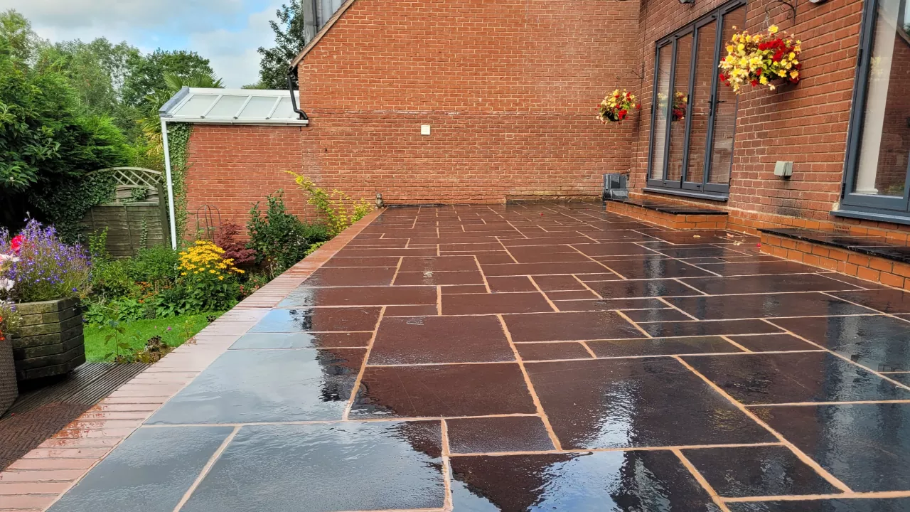 A garden patio with dark tiles contrasting with bright flowers