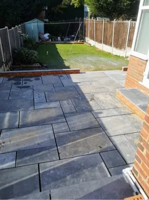 A grey slabbed patio that meets with grass