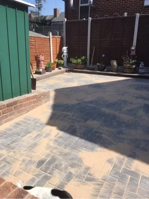 A grey brick patio, sand covers the surface