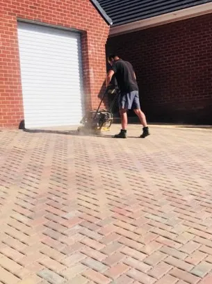 A man using a mechanical tool to hammer bricks into position