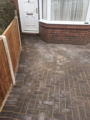 A grey brick drive infront of a house