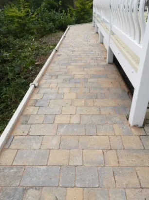 A grey cobble blocked pathway that returns between a property and garden