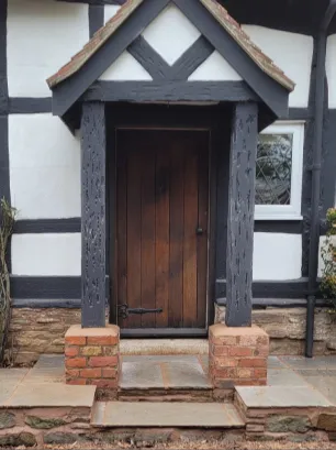 An old black and white property frontage. The ground is raised with slate slabs underfoot