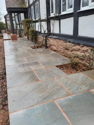 A grey coloured slab walkway to the front of an old black and white building